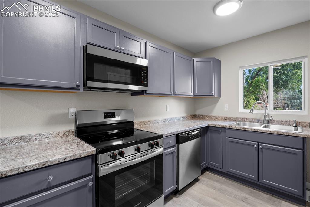 Image 7 of 25: Kitchen with appliances with stainless steel finishes, gray cabinets, light