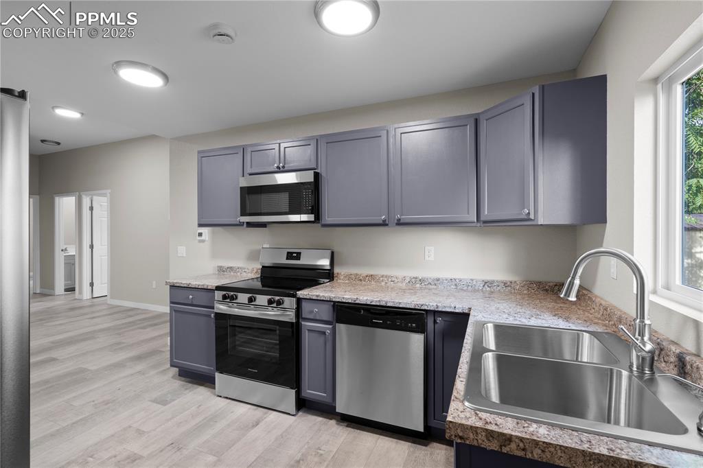 Image 8 of 25: Kitchen featuring appliances with stainless steel finishes and light wood-s