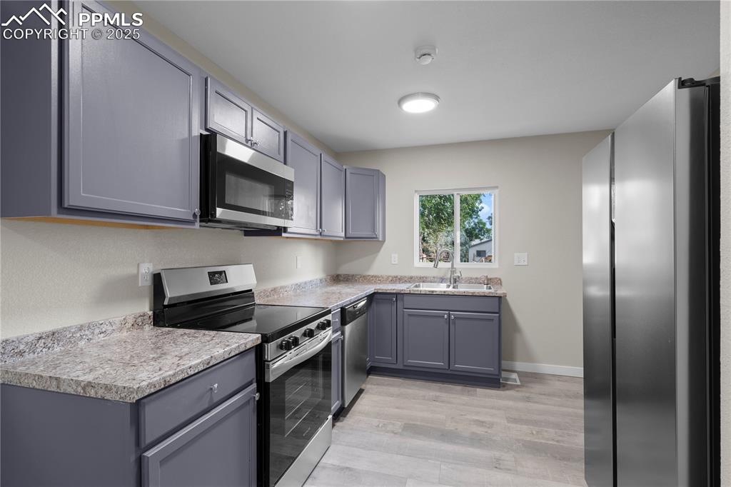 Image 9 of 25: Kitchen with stainless steel appliances, light wood-type flooring, gray cab