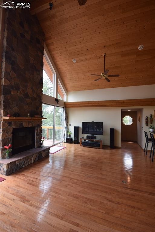 Image 10 of 44: Unfurnished living room with high vaulted ceiling, a fireplace, light wood-