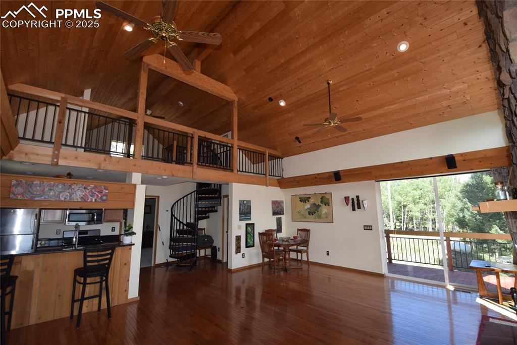 Image 12 of 44: Living area with a ceiling fan, a towering ceiling, stairs, dark wood-style