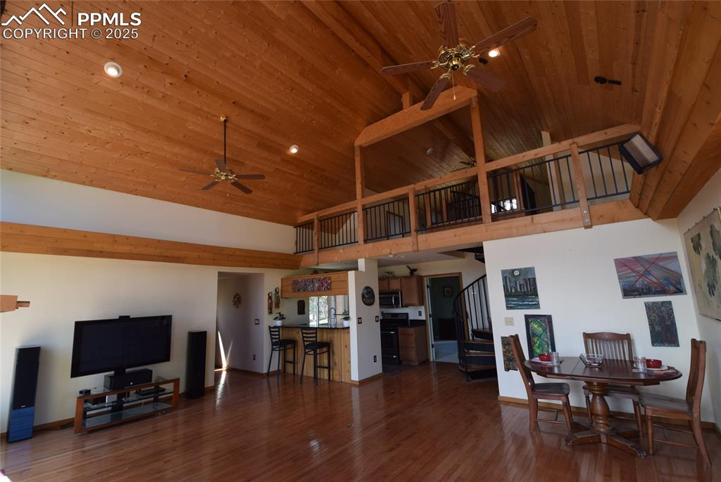 Image 14 of 44: Living room featuring stairs, dark wood-type flooring, ceiling fan, high va