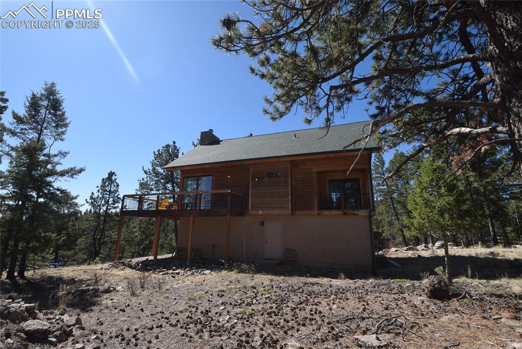 Image 34 of 44: Back of property featuring a deck, roof with shingles, and a chimney