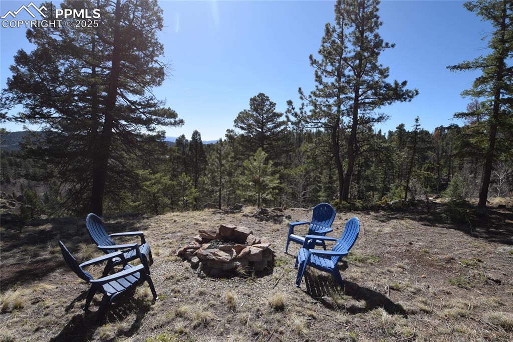 Image 4 of 44: View of yard with an outdoor fire pit and a view of trees