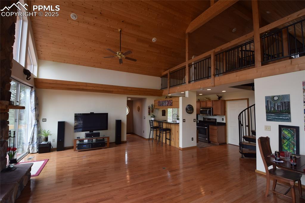 Image 9 of 44: Living room with high vaulted ceiling, stairs, light wood-style floors, cei
