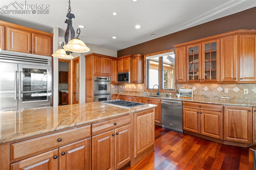 Image 13 of 40: Kitchen featuring rich wood cabinets, granite counters, a large center isla