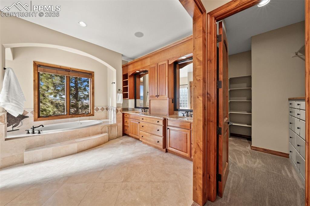 Image 20 of 40: The primary bathroom showcases dual vanities with rich wood cabinets and gr