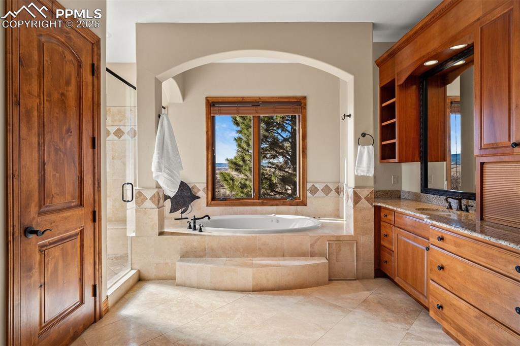 Image 21 of 40: Primary bathroom with a soaking tub set beneath mountain views, complemente