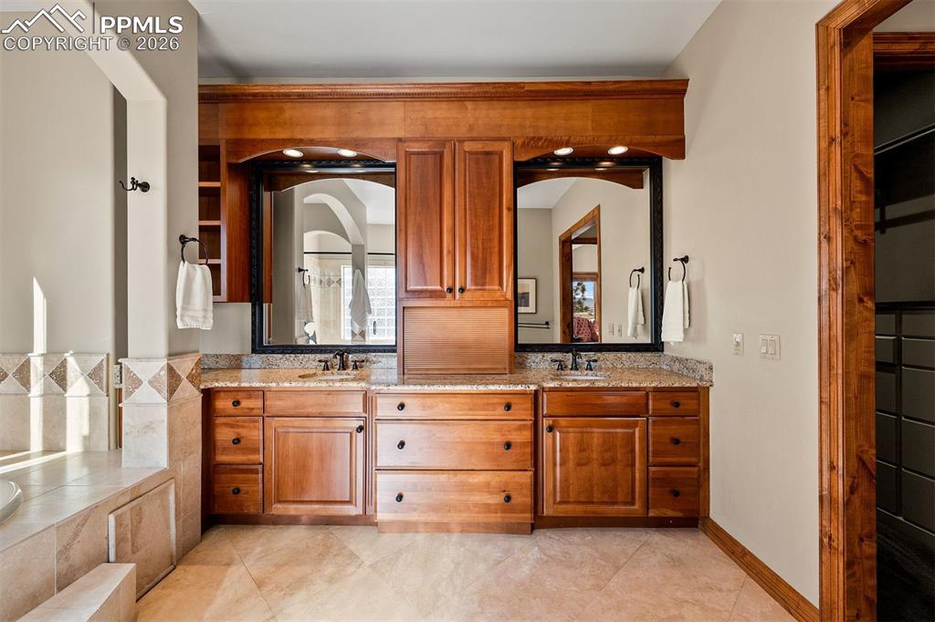 Image 22 of 40: Primary bathroom featuring dual vanities, granite counters, and rich wood c
