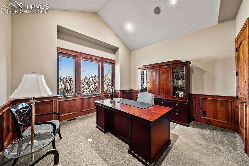 Image 24 of 40: Main level bedroom currently used as an office with rich wood wainscotting