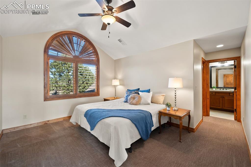 Image 28 of 40: Upper level bedroom (bedroom 3) with vaulted ceilings, distinctive arched w