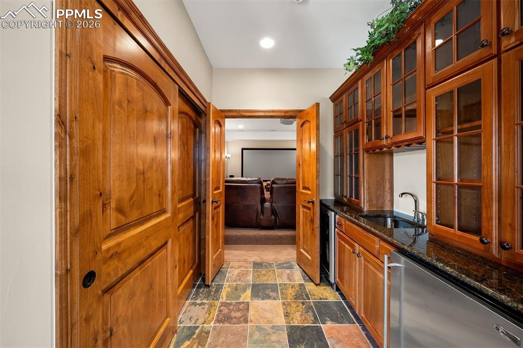 Image 33 of 40: Lower level wet bar with glass-faced cabinets leading directly into the the