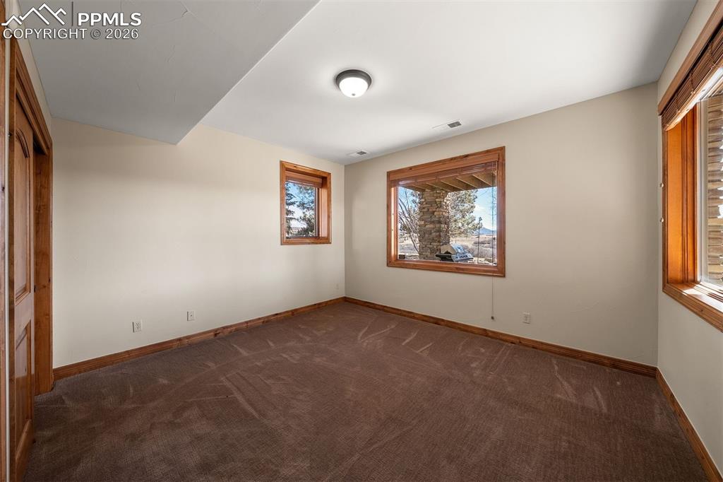 Image 37 of 40: Lower level bedroom (bedroom 5) with multiple windows, natural light, and a
