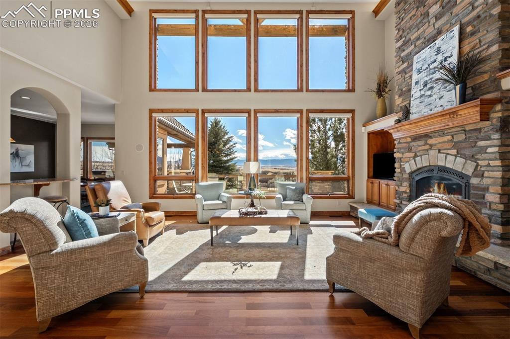 Image 8 of 40: Great room with dramatic double height windows, a floor to ceiling stone fi