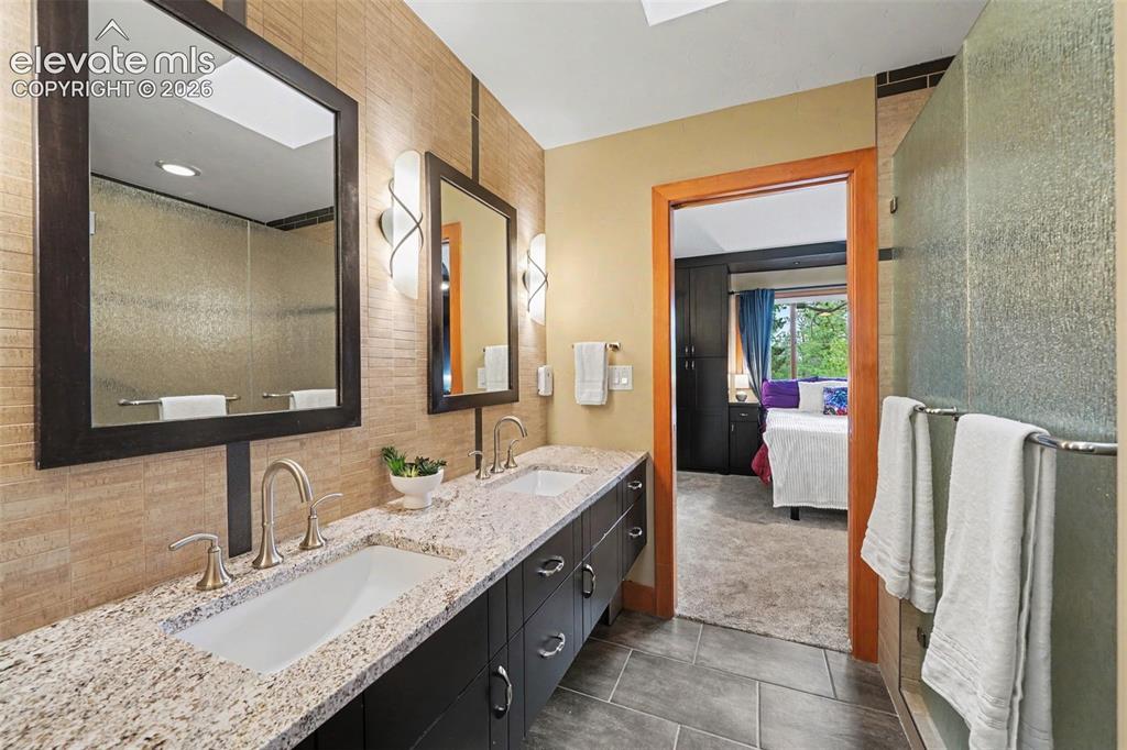 Image 16 of 30: The spacious en-suite primary bathroom is designed with both comfort and st