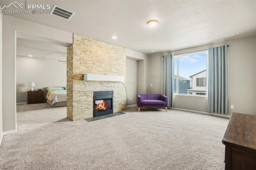 Image 10 of 35: Living room with a textured ceiling, a fireplace, and light carpet