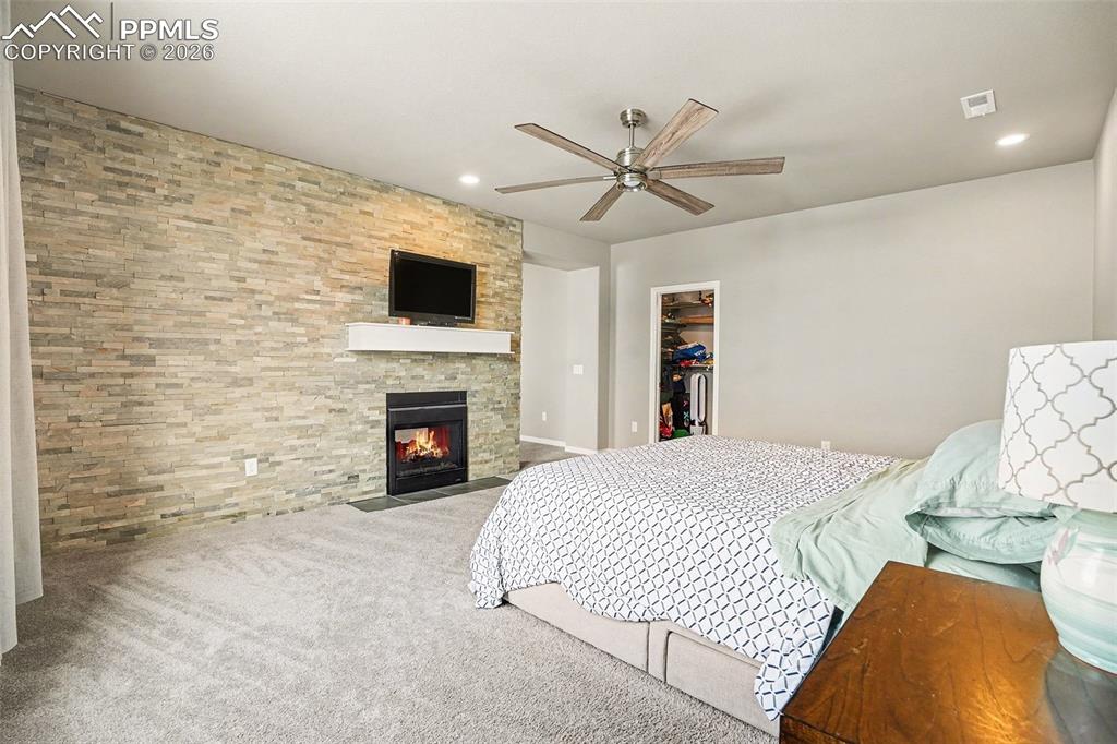 Image 11 of 35: Carpeted bedroom featuring a fireplace, ceiling fan, a walk in closet, and 