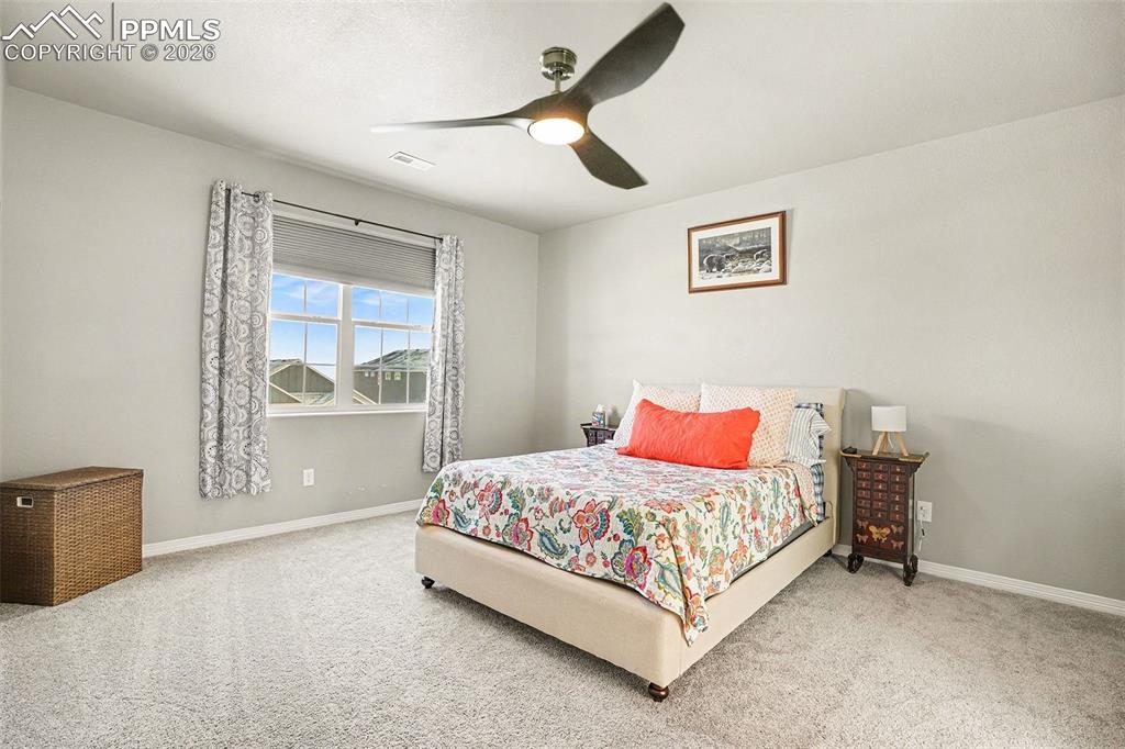 Image 15 of 35: Bedroom with a ceiling fan and carpet flooring