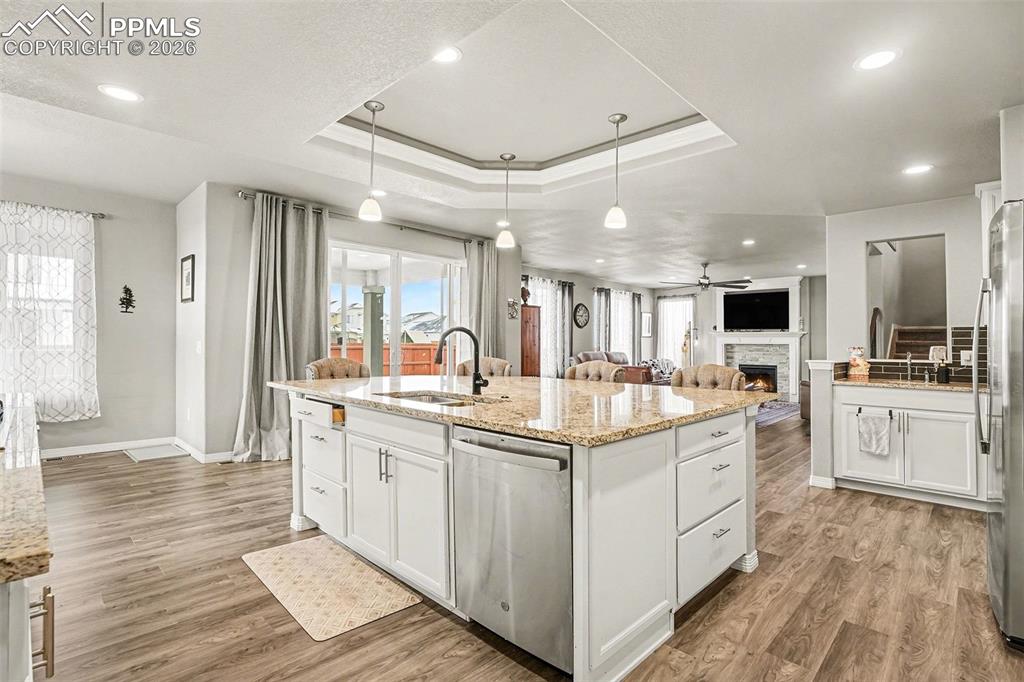 Image 6 of 35: Kitchen with white cabinets, a fireplace, open floor plan, appliances with 