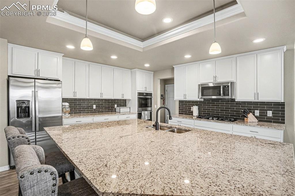 Image 7 of 35: Kitchen with ornamental molding, white cabinetry, appliances with stainless