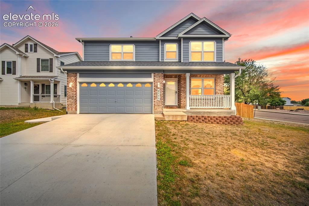 Caption: Twilight front exterior highlighting the home’s inviting curb appeal, covered front porch, two-car g