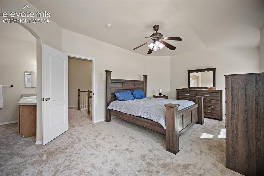 Image 12 of 41: Generously sized primary bedroom with vaulted ceiling, ceiling fan, ample n