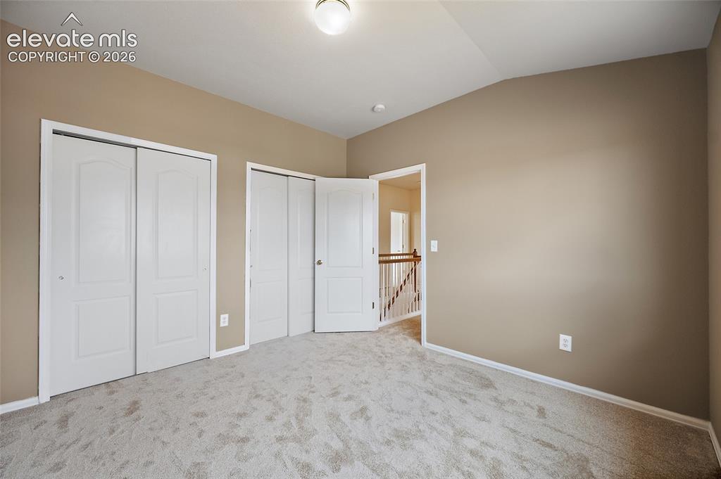 Image 23 of 41: Alternate view of the secondary bedroom showing dual closet areas, vaulted
