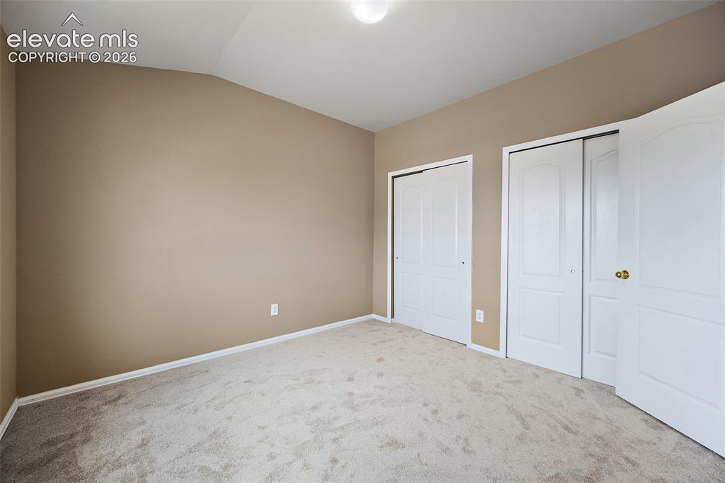 Image 24 of 41: Additional upstairs bedroom with vaulted ceiling, ceiling fan, large window