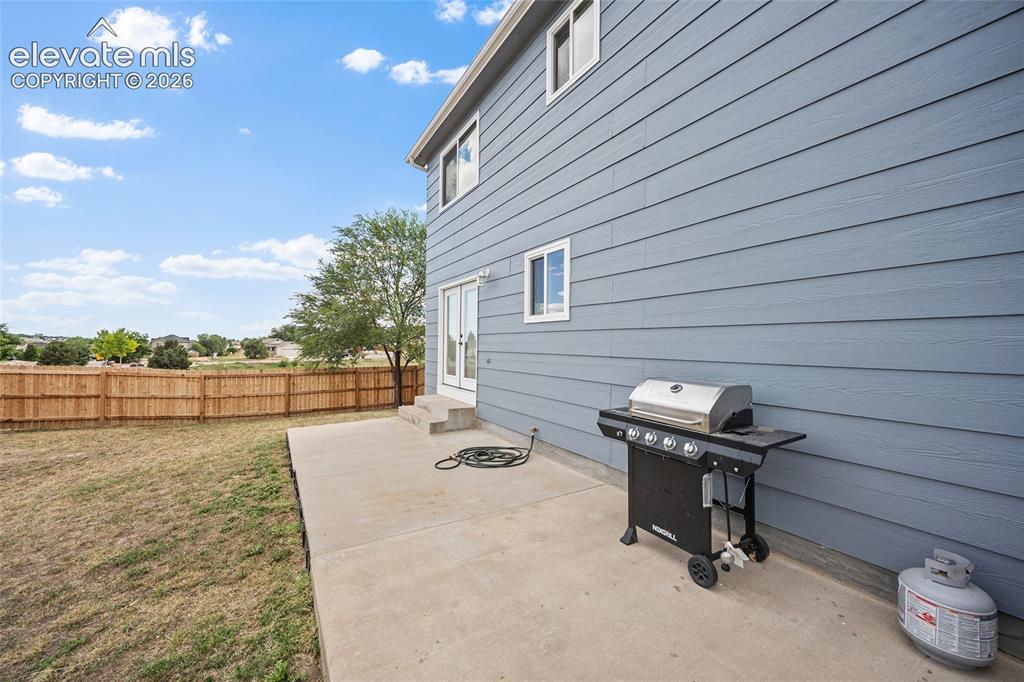 Image 29 of 41: Concrete patio and fenced backyard provide flexible outdoor space for dinin