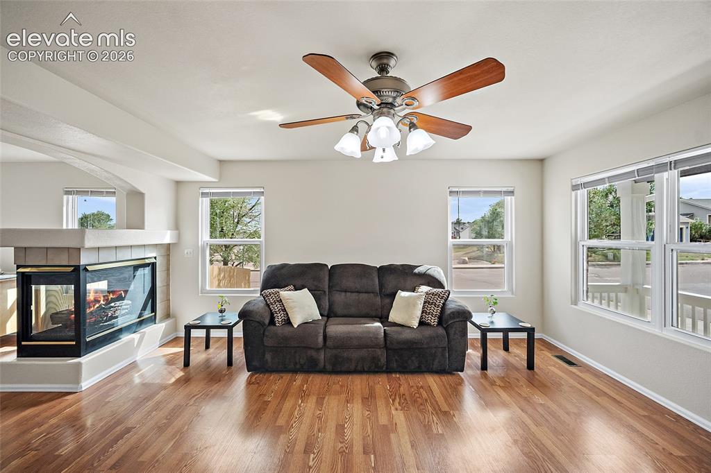 Image 3 of 41: Bright living room with multiple windows, hardwood floors, ceiling fan, and