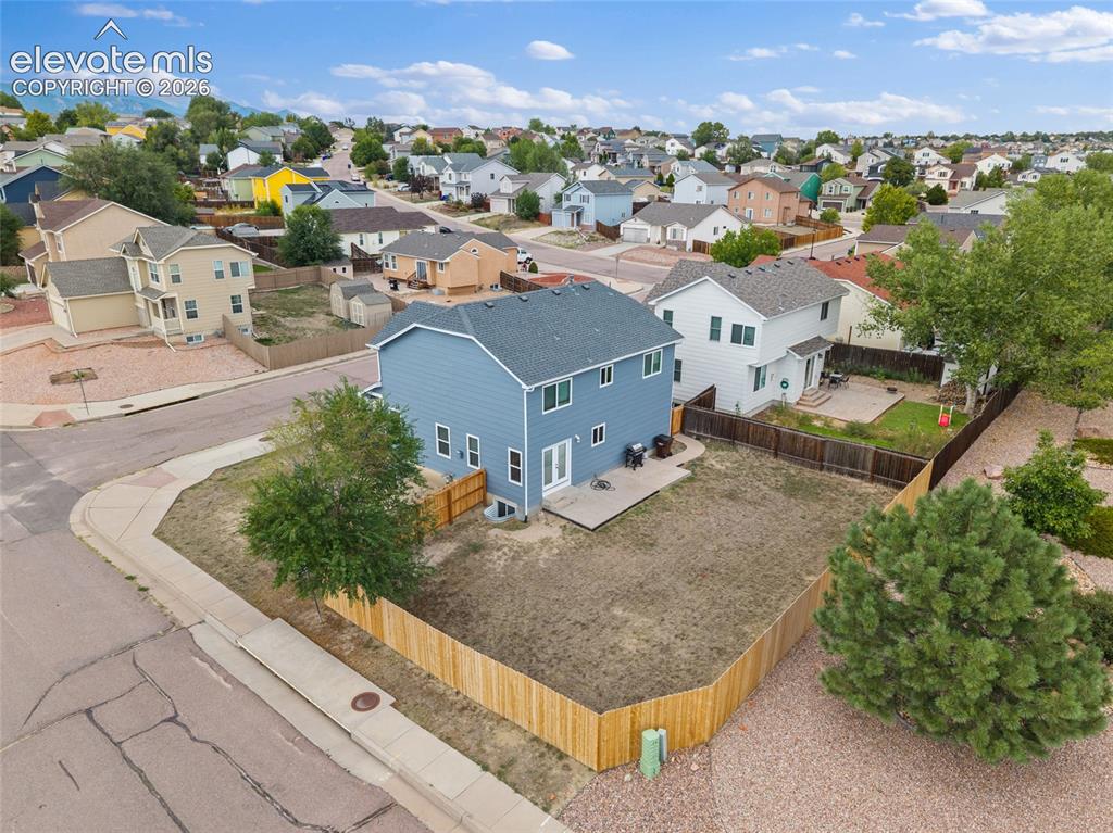 Image 32 of 41: Elevated rear view showing the fenced backyard, concrete patio, corner-lot