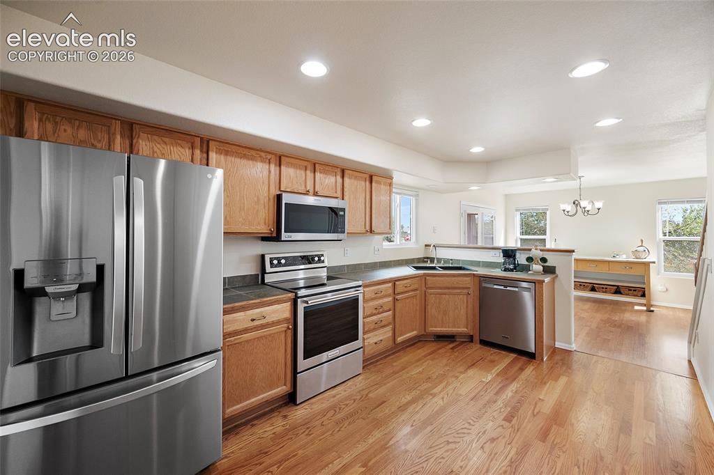 Image 4 of 41: Bright kitchen with hardwood flooring, oak cabinetry, stainless steel appli