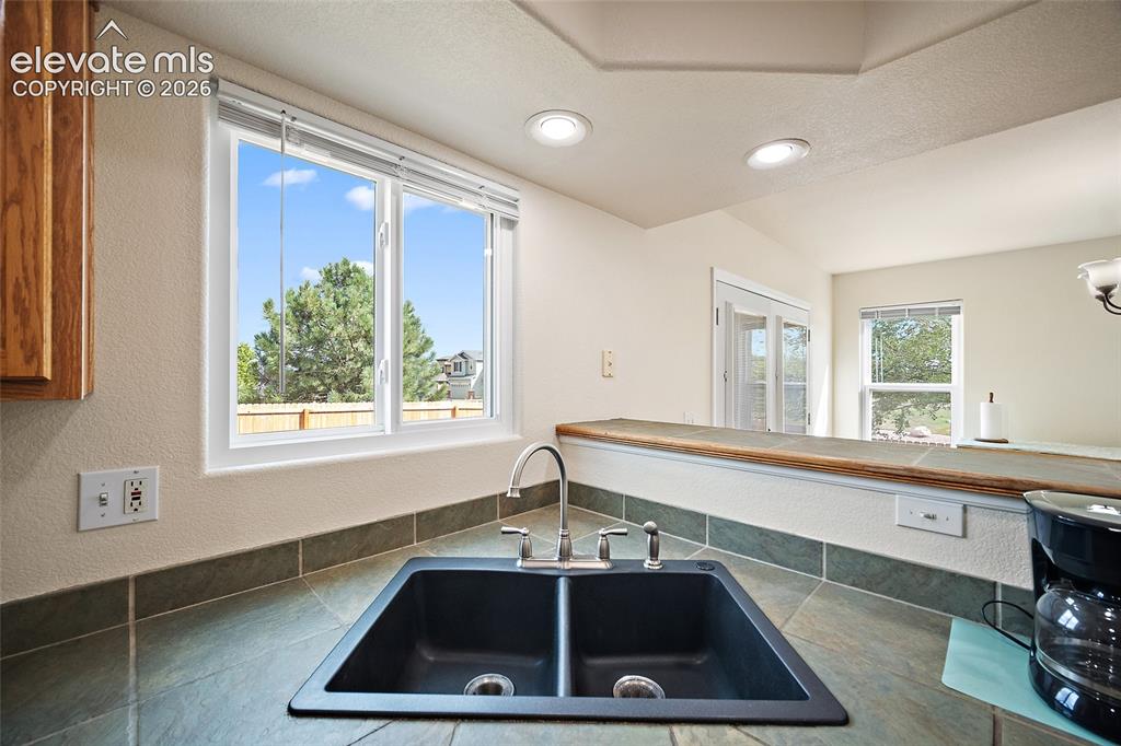 Image 5 of 41: Kitchen sink area with double-basin sink, tile countertops, recessed lighti