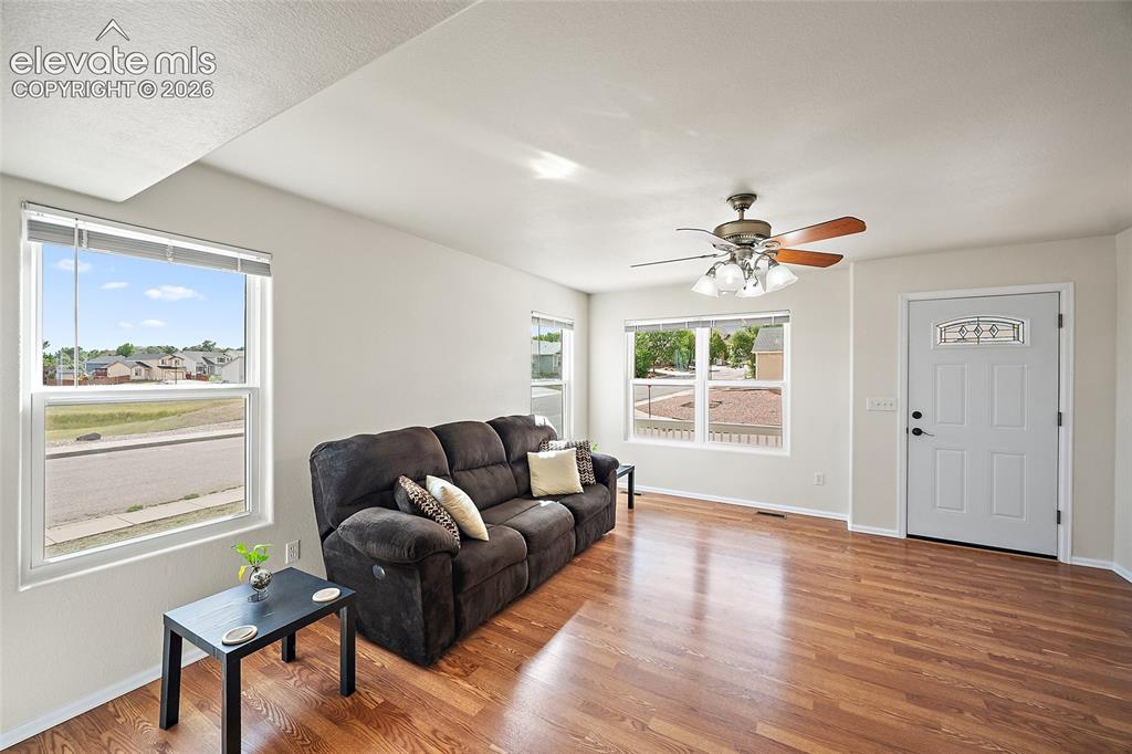 Image 8 of 41: Main-level living room with hardwood floors, abundant natural light, ceilin