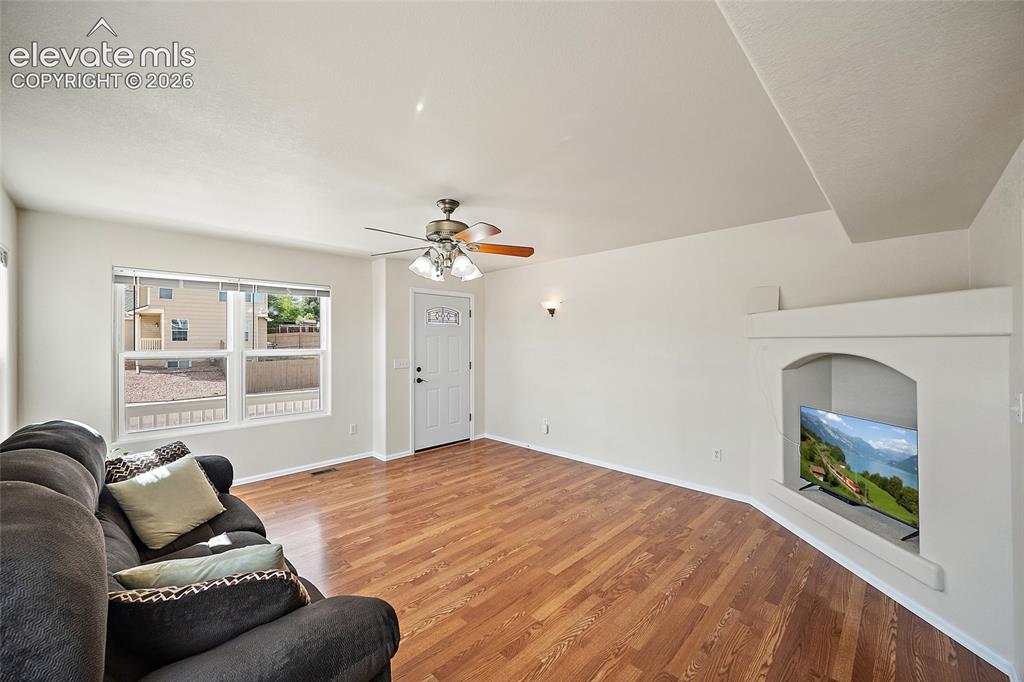 Image 9 of 41: Spacious living room featuring hardwood flooring, ceiling fan, front-facing
