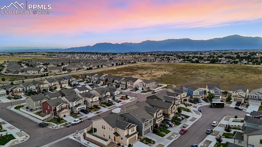Image 45 of 47: Aerial view of home and neighborhood with beautiful sunset mountain views.