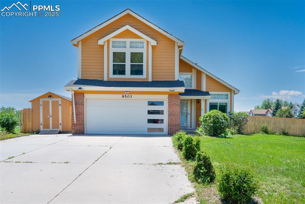 Caption: Traditional-style house with concrete driveway, a garage, brick siding, and a shed