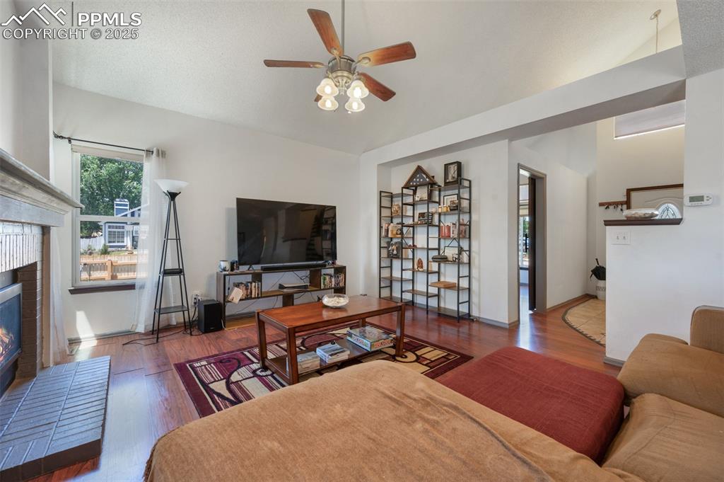 Image 16 of 50: Living room featuring a ceiling fan, wood finished floors, a fireplace, and