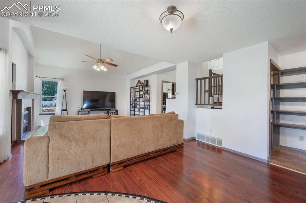 Image 18 of 50: Living room with a ceiling fan, wood finished floors, a textured ceiling, a