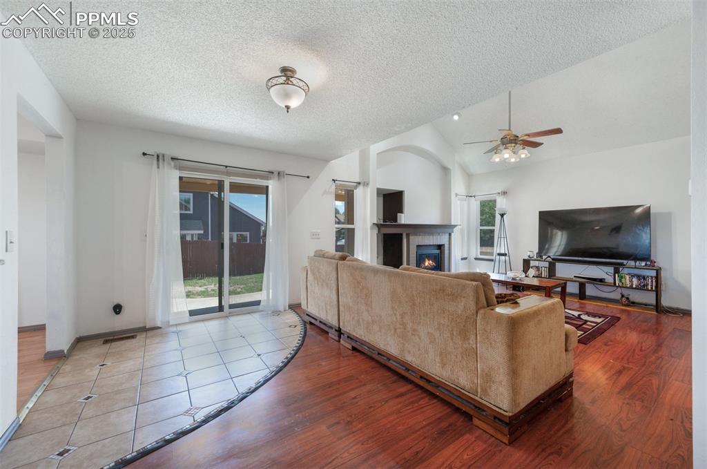 Image 20 of 50: Living room featuring a ceiling fan, a textured ceiling, lofted ceiling, a