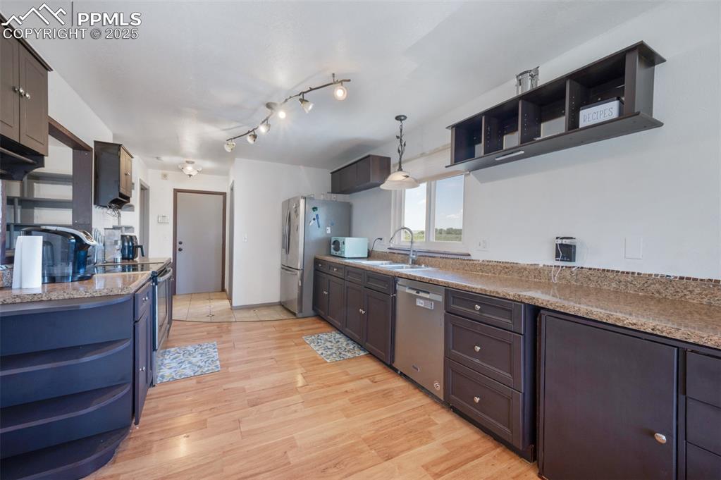 Image 21 of 50: Kitchen with open shelves, appliances with stainless steel finishes, light