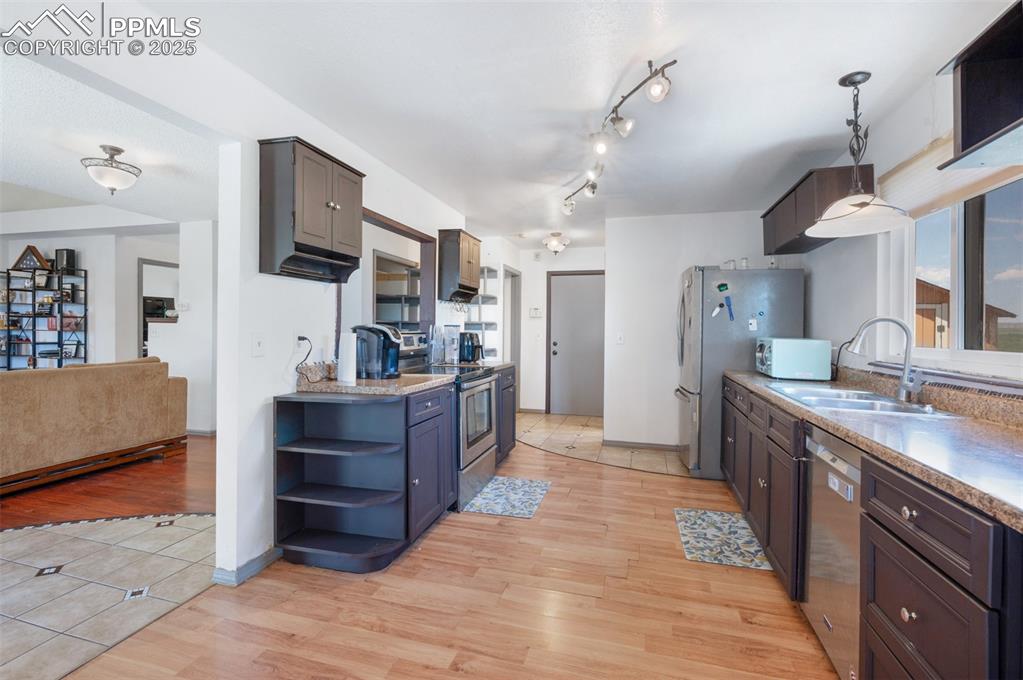 Image 22 of 50: Kitchen featuring stainless steel appliances, open shelves, and light wood-