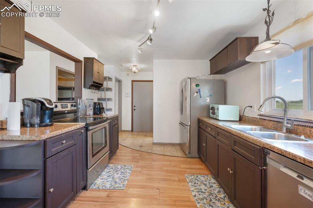 Image 23 of 50: Kitchen featuring stainless steel appliances, light wood-style flooring, ha