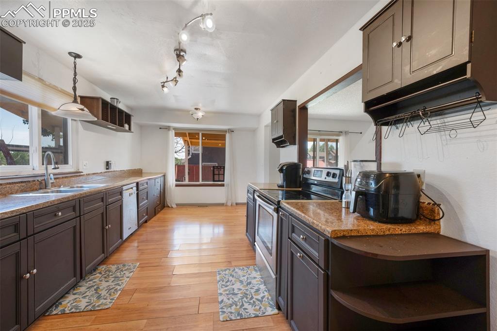 Image 26 of 50: Kitchen featuring stainless steel range with electric cooktop, open shelves