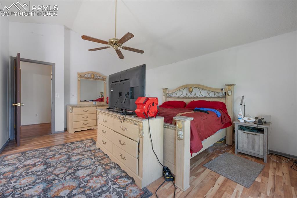 Image 39 of 50: Bedroom with light wood-style flooring, vaulted ceiling, and a ceiling fan