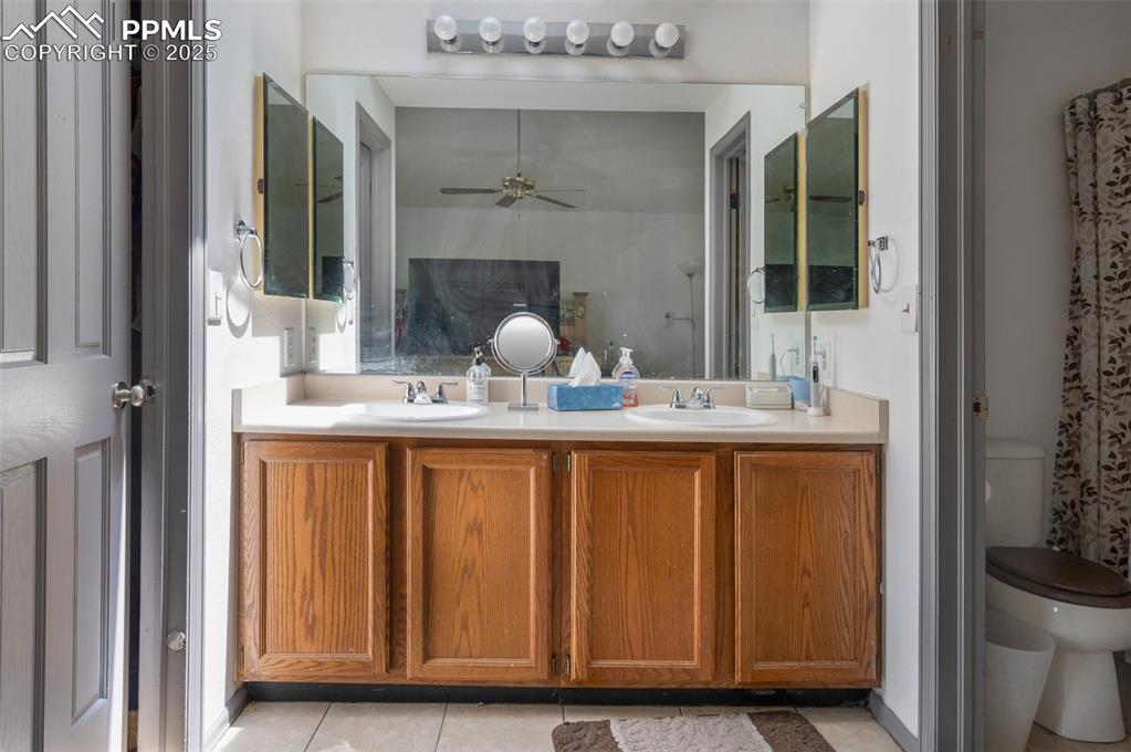 Image 41 of 50: Bathroom featuring double vanity, a ceiling fan, and tile patterned floorin