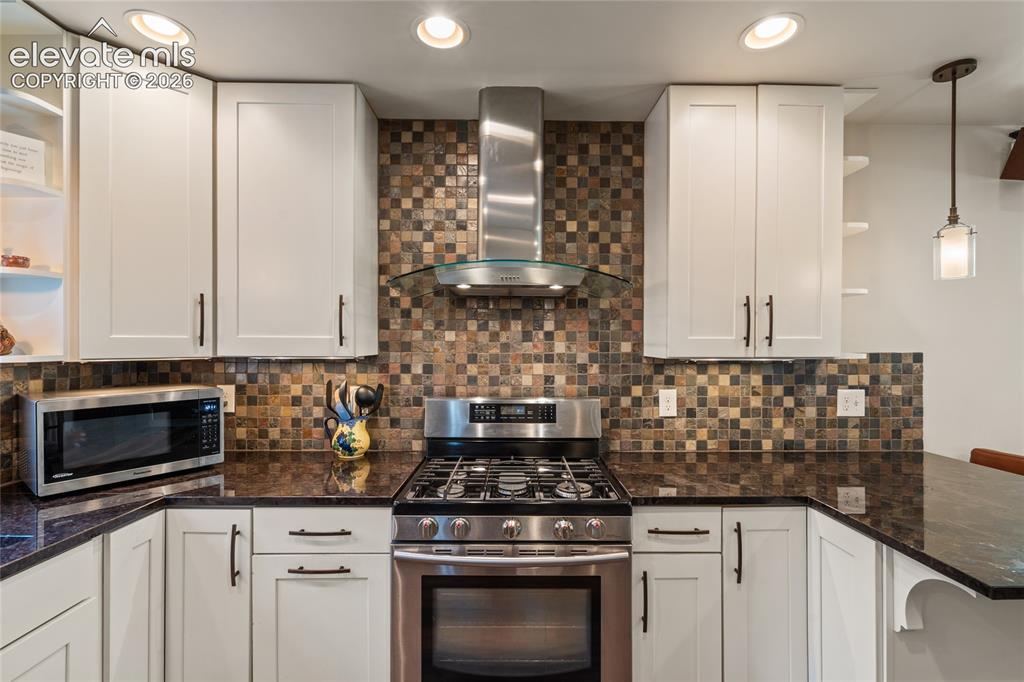 Image 9 of 38: Main house Kitchen includes stainless gas range and vent hood