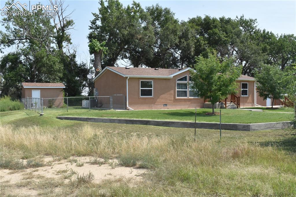 Caption: View of side of property with crawl space and stucco siding
