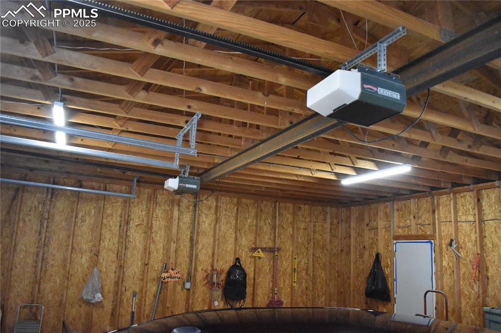 Image 15 of 47: Garage featuring a garage door opener and wooden walls