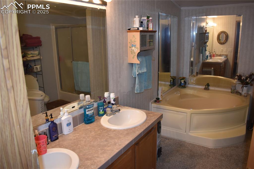 Image 21 of 47: Bathroom featuring a bath, double vanity, a shower stall, wallpapered walls
